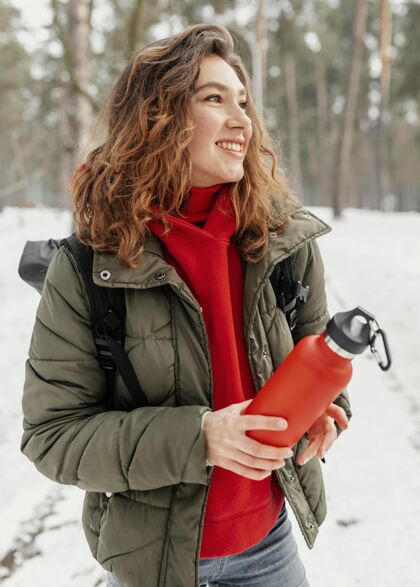 冬季拿着瓶子的中枪女人自然旅行瓶子