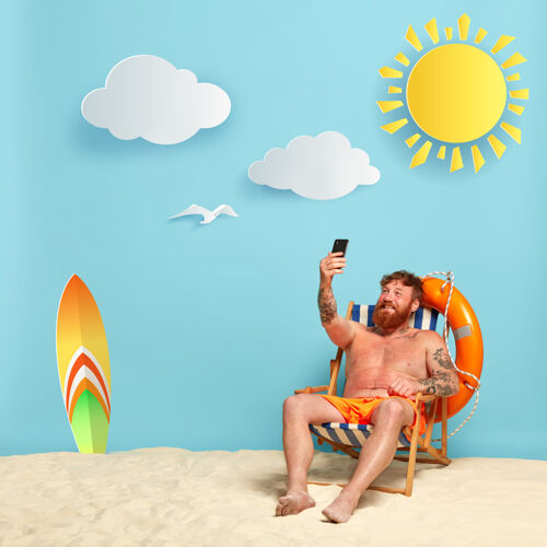 放松快乐的赤膊胡子红发男子在海滩上摆姿势充气成人电话