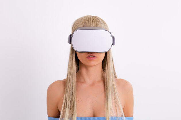 女人摄影棚照片中一个年轻迷人的女子穿着温暖的蓝色时尚西装 戴着虚拟现实眼镜在白色的视觉不穿衣服裸体