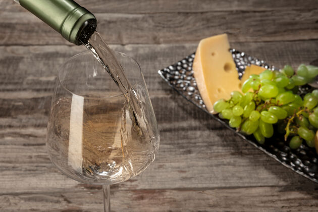 边界木桌上放着一瓶和一杯带水果的白葡萄酒吃切达饮料
