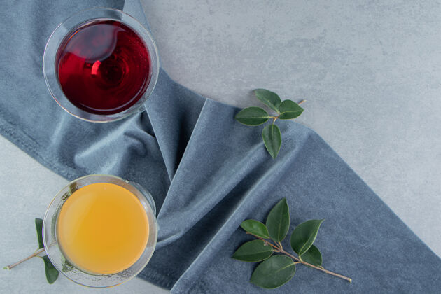 美味两杯果汁和叶子放在毛巾上 大理石背景高质量的照片牙粉糖果汁