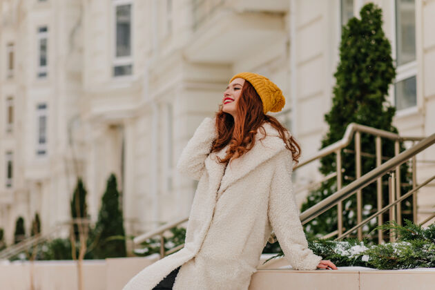一月令人高兴的穿着考究的女士在冬天放松穿着长外套的快乐姜汁女孩的户外肖像女性寒冷散步