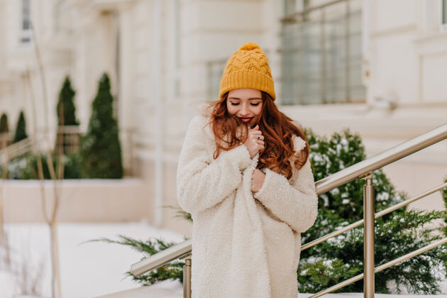 灵感在冬天摆姿势的快乐的白人女孩可爱的年轻女士站在绿色的冷杉附近冬季寒冷的天气雪