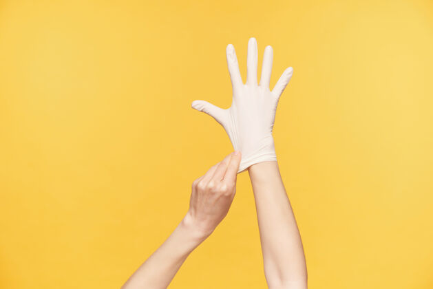 庄稼摄影棚照片中 年轻女子举起的手在橙色背景上摆姿势 保持所有手指分开 同时另一只手戴上白色橡胶手套手臂女性举