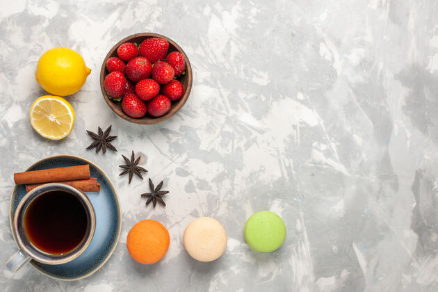 健康俯瞰法国麦卡龙与茶和新鲜草莓的白色表面糖甜食浆果
