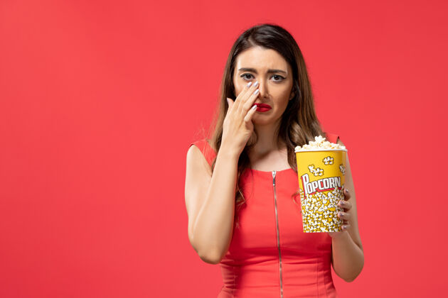 女士正面图：年轻女子拿着爆米花包在看电影的时候哭了性感而电影