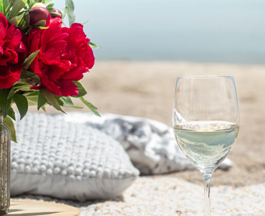 海滩带着鲜花和香槟的海边浪漫野餐度假的概念香槟玻璃浪漫