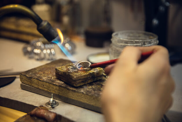特写近距离接触珠宝商的手 金匠用专业工具用宝石制作金戒指美丽工作珍贵
