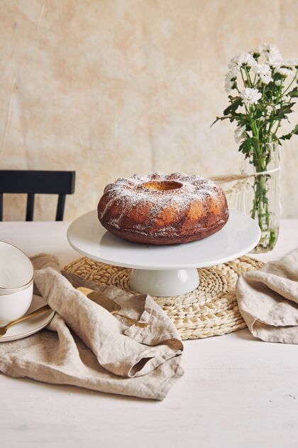 奶油美丽的镜头美味的环蛋糕放在一个白色的盘子和一个白色的花靠近它晚餐面包房桌子