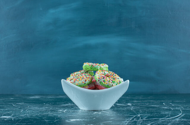 盘子一个白色的碗在蓝色的背景上装满了甜甜圈高质量的照片食物奶油很多