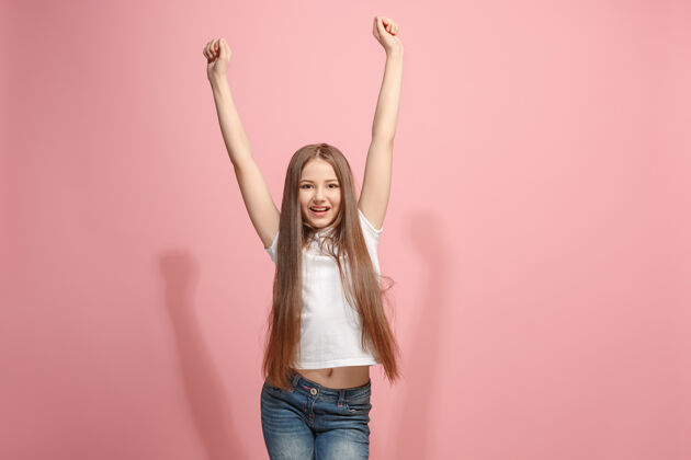 粉丝赢得成功快乐的少女庆祝成为赢家粉红色工作室墙上高加索女模特的动态形象胜利 喜悦的概念人类面部情感的概念流行的颜色休闲青少年成人