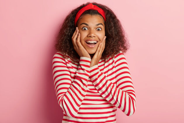 正面兴奋的卷发少女穿着条纹红毛衣摆姿势的照片女性女士大笑