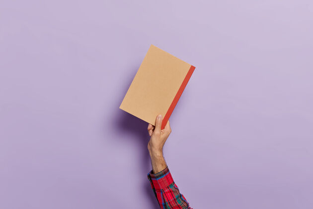 人一只手拿着空日记孤立在紫罗兰之上衬衫空记事本