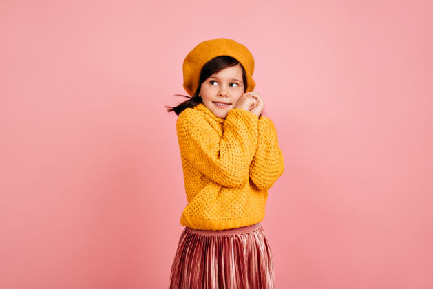 服装害羞的小女孩在粉红色的墙上摆姿势穿黄色衣服的可爱的孩子积极微笑黑发