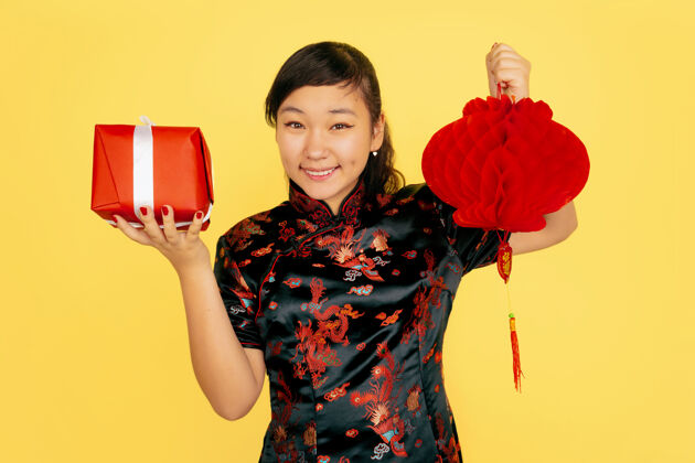 年轻带着灯笼和礼物摆姿势 微笑着2020年中国新年快乐黄色背景上的亚洲少女肖像身着传统服装的女模特看起来很快乐复制空间庆祝情感灯笼