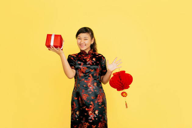 祝福摆着灯笼和礼物 微笑着中国新年快乐黄色背景上的亚洲少女肖像身着传统服装的女模特看起来很快乐复制空间庆祝肖像服装
