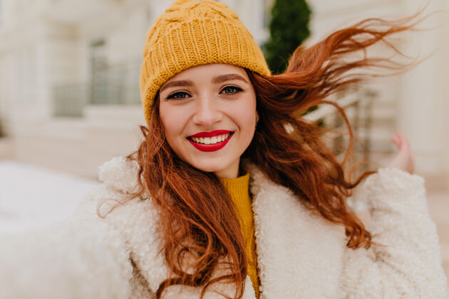街道幸福的红唇长发女人在冬日周末自拍可爱的戴着帽子的姜女在表达幸福冬季卷发寒冷