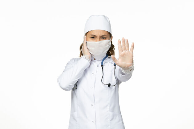 到期正面图：年轻女医生 穿着白色医疗服 白色办公桌上有冠状病毒导致的无菌口罩大流行疾病灭菌