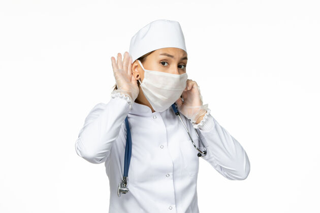 工作正面图年轻女医生穿着白色医疗服 由于白色表面有冠状病毒 戴着口罩冠状病毒职业正面