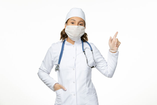 医生正面图年轻女医生穿着白色的医疗服 由于白色表面有冠状病毒 戴着无菌口罩正面大流行疾病