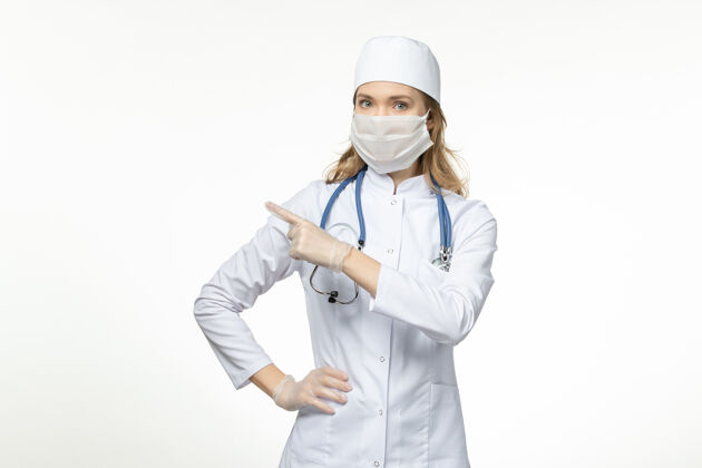 穿戴正面图年轻女医生穿着医疗服戴着防护口罩由于白色表面有冠状病毒正面护士大流行
