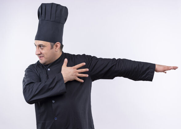 穿男厨师身穿黑色制服 头戴厨师帽 一边看一边用手指着一边站在白色背景上指点站旁边