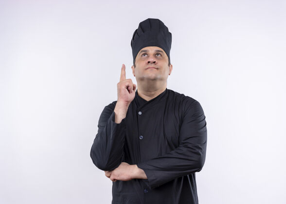 手指男厨师身穿黑色制服 头戴厨师帽 食指朝上 站在白色背景上仰望目录站帽子