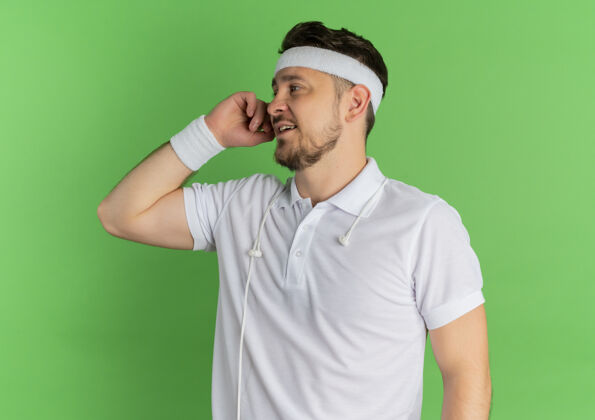 健康身穿白衬衫 头箍 脸上挂着微笑的年轻健身男子站在绿色背景下站微笑男人