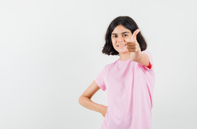 粉色小女孩穿着粉色t恤向上竖起大拇指 看上去很乐观正面视图显示美丽未成年