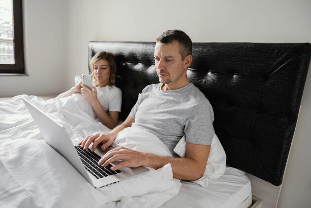 手机夫妇在床上使用设备笔记本电脑男人房子