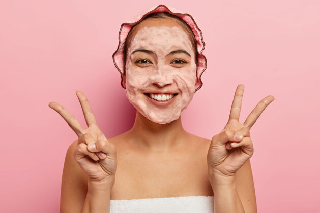 浴室美丽的亚洲女人双手做和平手势 积极微笑 用肥皂泡洗脸 讲究卫生 沐浴后享受清新享受女人面部