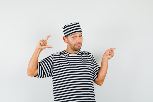 休闲一个穿着条纹t恤 戴着帽子的年轻人 指着旁边的小尺寸标志秀自信指点
