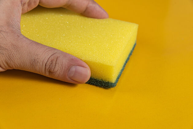 洗黄色背景上拿着厨房海绵的男人盘子产品卫生