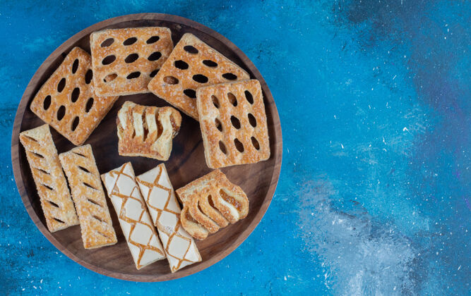 牙刷木制托盘上的饼干 蓝色背景高品质照片甜点饼干配料