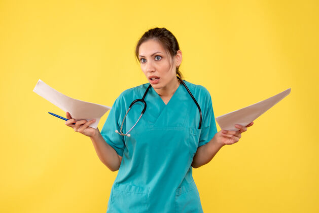 黄正面图年轻女医生穿着医用衬衫拿着黄色背景的纸张分析纸持医学