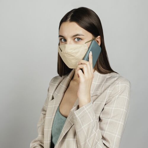 模特肖像时尚的女人用手机带面具保护外科口罩年轻