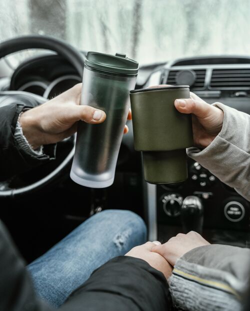 自然一对夫妇在车上 而在公路旅行祝酒与热饮料的后视图冒险旅行男人