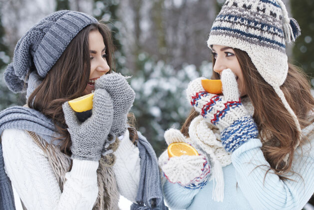 帽子年轻的朋友在吃橘子年轻女人寒冷