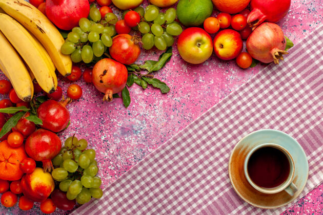 生的顶视图新鲜水果组成五颜六色的水果与一杯茶在粉红色的表面醇香的柑橘杯子