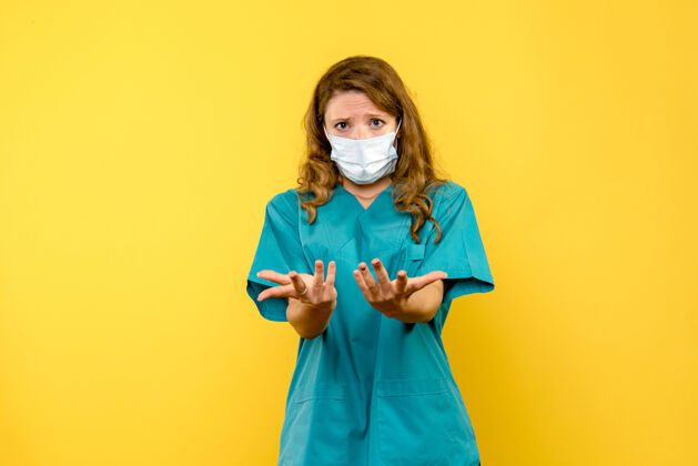 面罩黄色空间里戴着面具的女医生的正视图医院制服听诊器