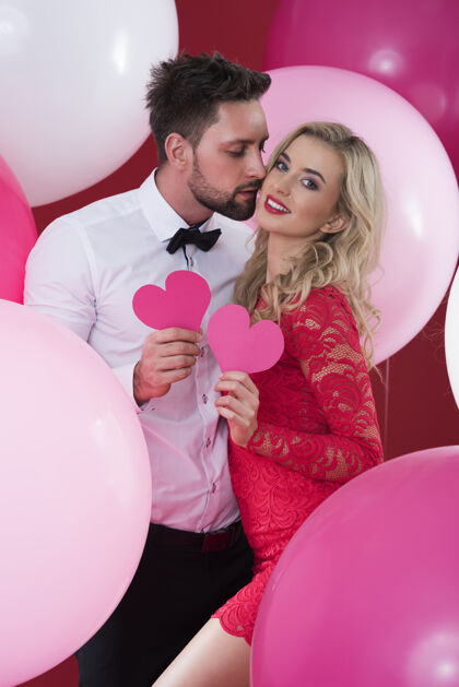 女人味相爱的情侣捧着纸做的粉红色的心情人异性伴侣气球