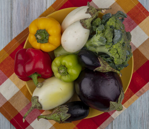 顶部顶视图的蔬菜 如胡椒花椰菜和茄子在板上的格子布在木制背景蔬菜胡椒盘子
