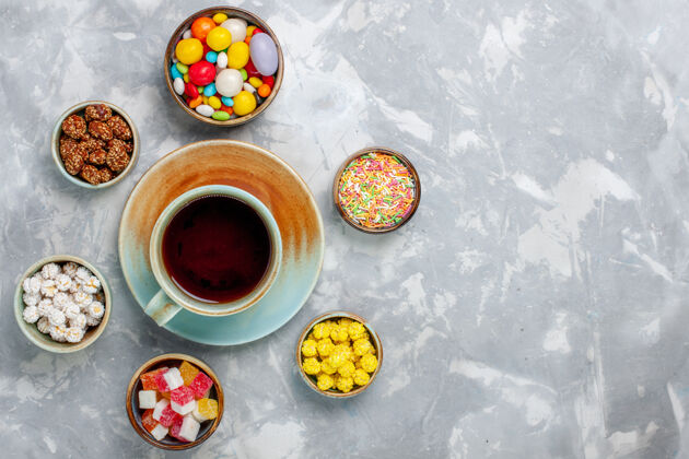 五颜六色在白色的桌子上俯瞰不同颜色的糖果和果酱以及一杯茶糖果蛋糕不同的