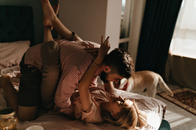 宠物男人和女友躺在床上拥抱在浪漫的气氛中妻子像猴子一样抱着丈夫肖像早餐情侣