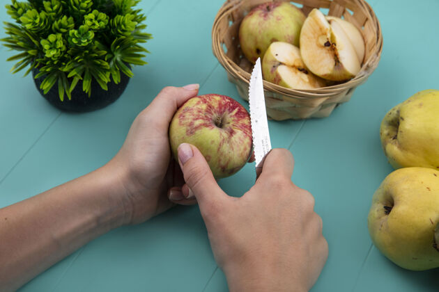 水果女性用刀在蓝色背景上切割新鲜苹果的手的俯视图刀新鲜水平
