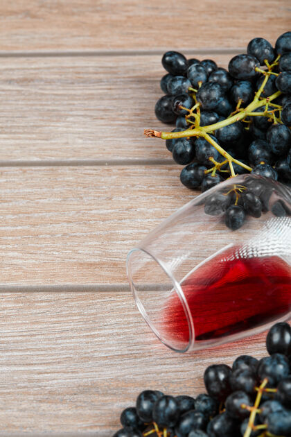 前视图木头表面一束黑葡萄和一杯葡萄酒的俯视图新鲜葡萄酒木材