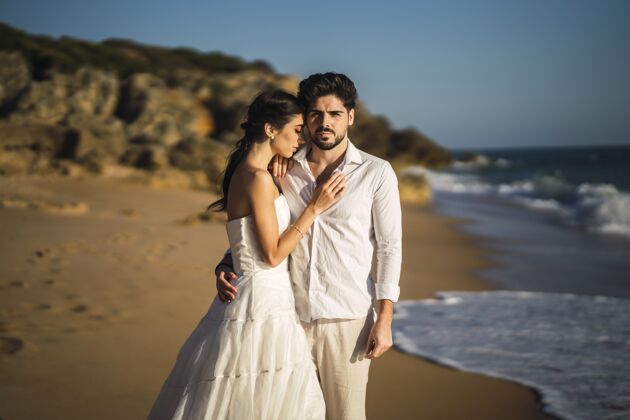 成人一对穿着白色衣服的白种人情侣在沙滩上拥抱 拍摄婚礼照片在一起女人户外