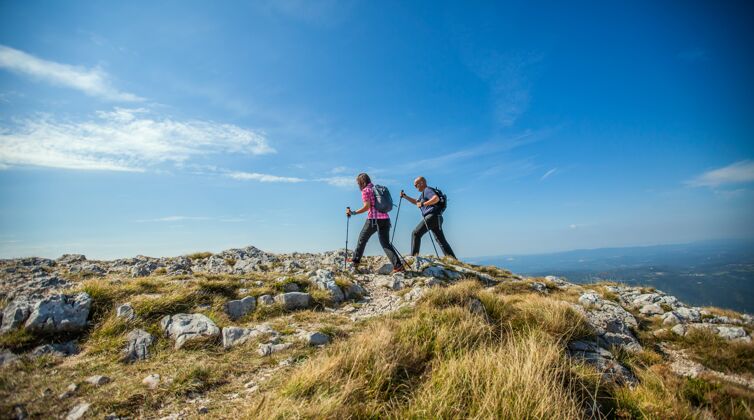 男人一对情侣在斯洛文尼亚的纳米高原上徒步旅行 蓝天映衬男人徒步旅行山