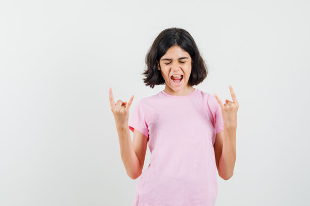 年轻小女孩做摇滚符号 同时尖叫在粉红色的t恤衫 看起来充满活力 前视图肖像符号可爱