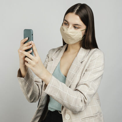 保护肖像时尚的女人用手机带面具自拍冠状病毒女人